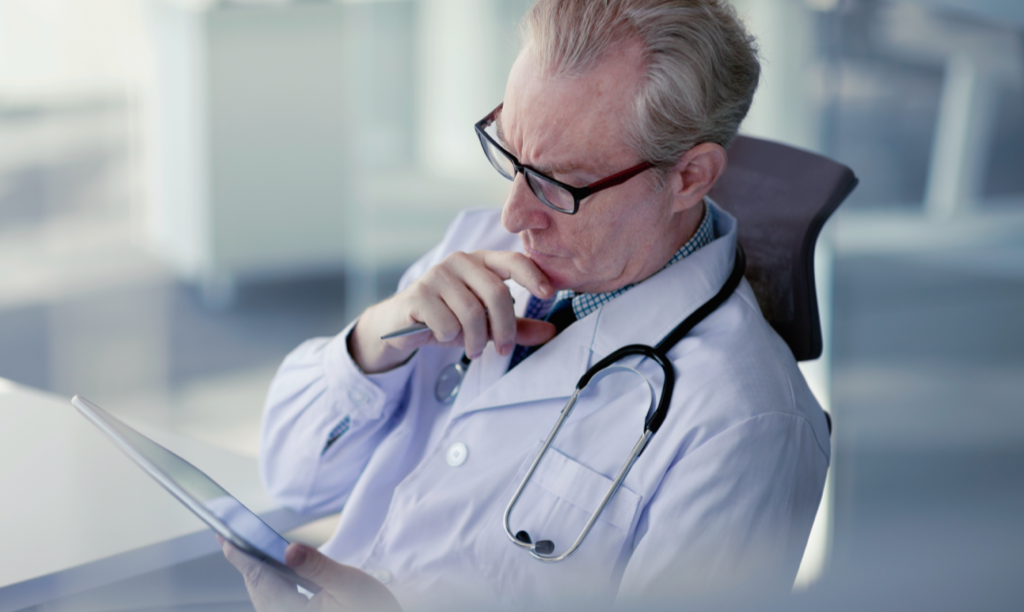 male doctor sitting in his office looking at his iPad
