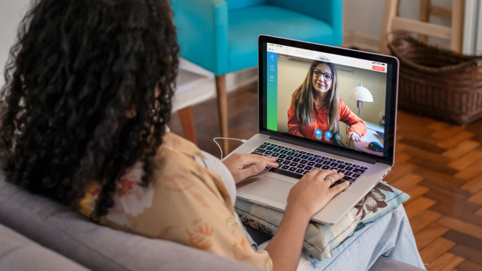 woman sitting with her laptop talking to a therapist at home