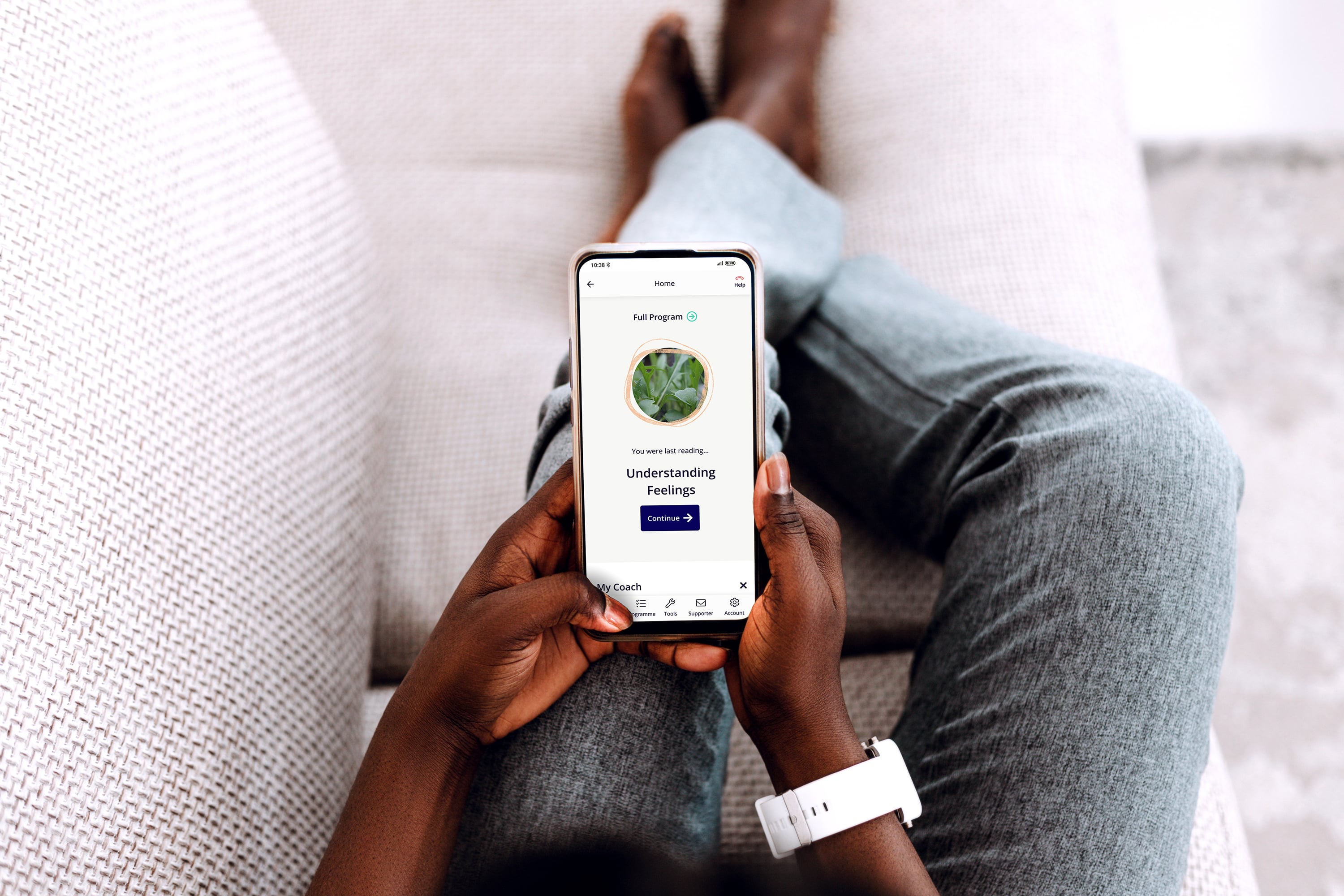 Person holding a smartphone displaying a mental health app, showing a 'Continue' prompt to resume the 'Understanding Feelings' lesson.