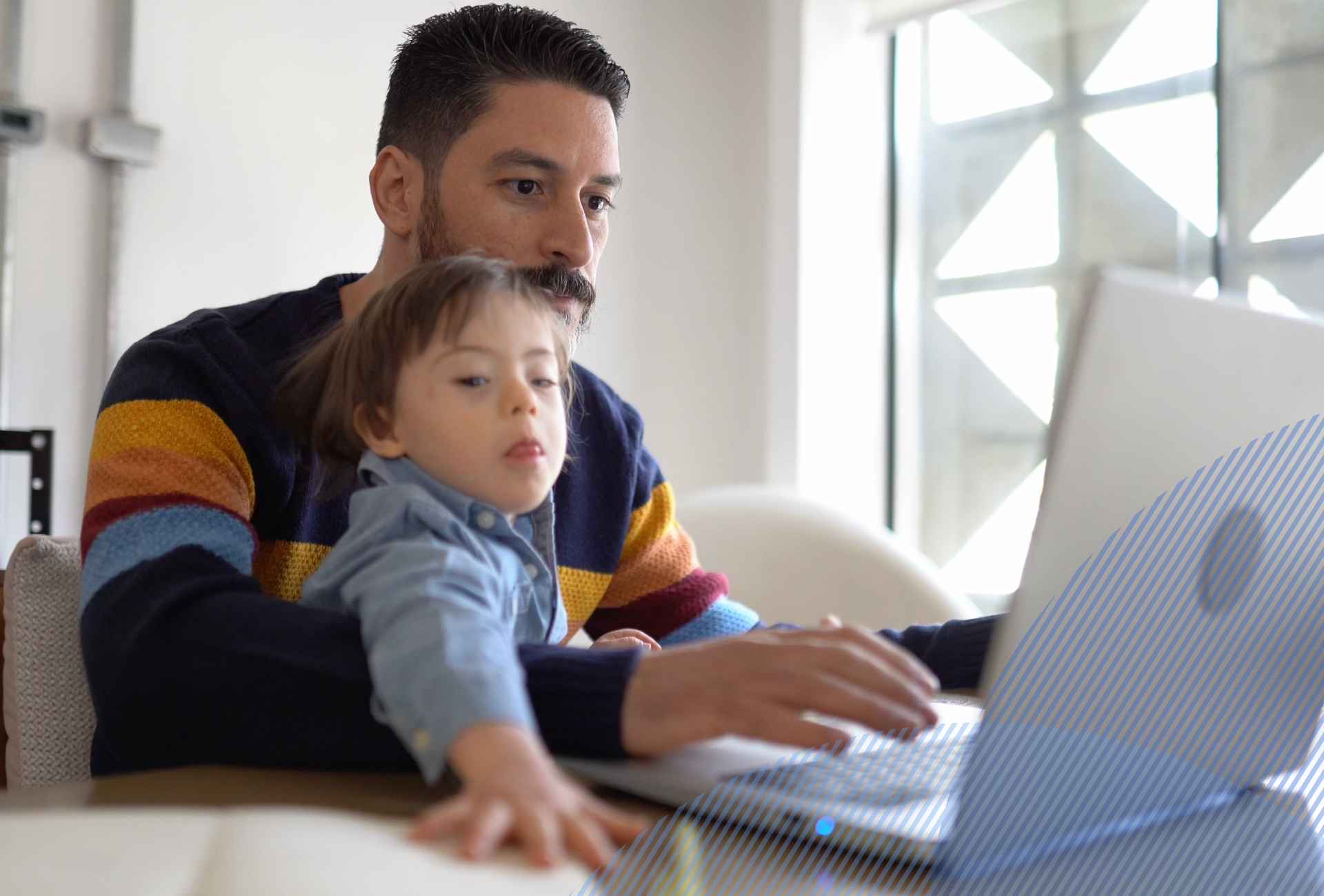 a man holding his son while talking to a provider on his laptop