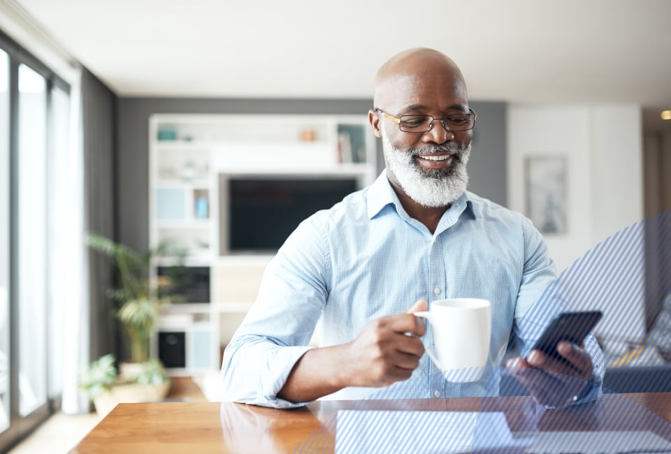 an older man holding a coffee mug and his phone