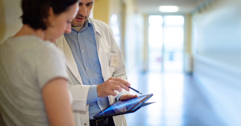 doctor explaining something to a patient on his tablet