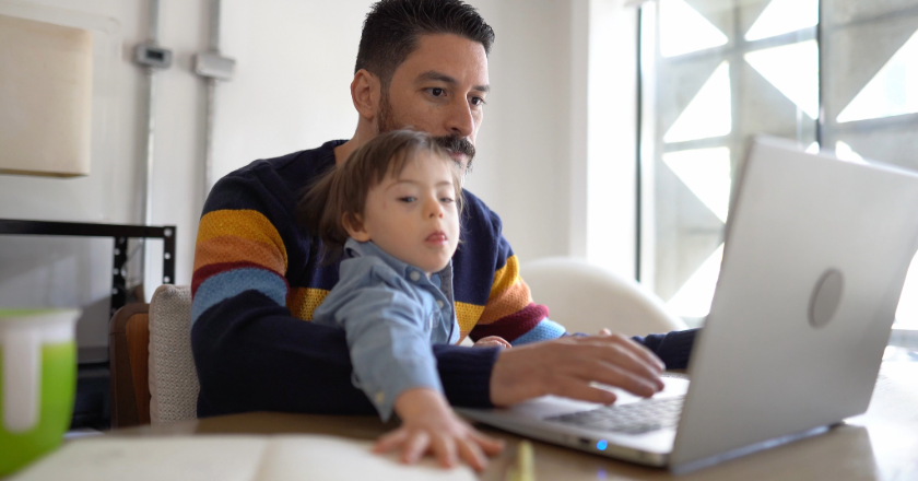 father and son on his lap looking at his computer