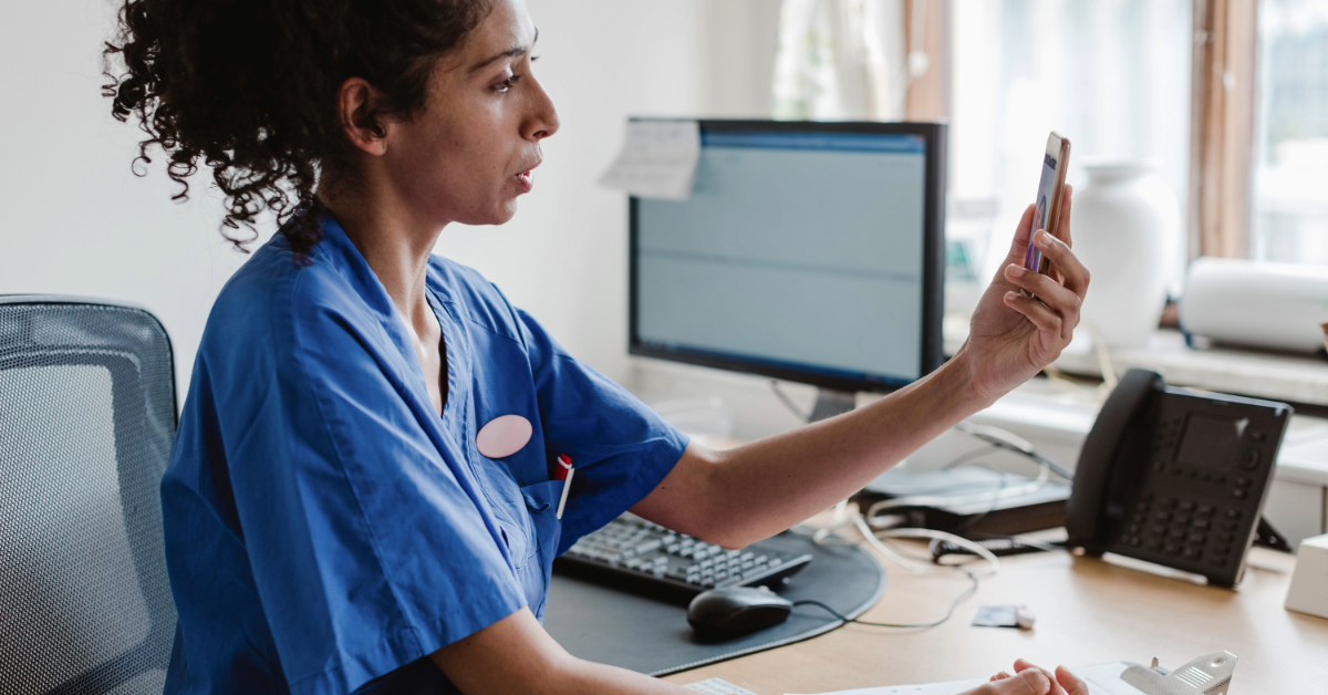 nurse holding her phone talking to a patient at her desk