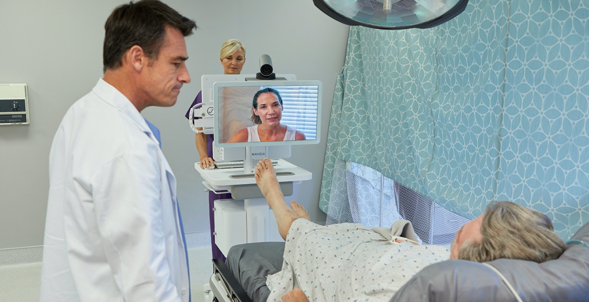 Provider facing patient in hospital bed with telemedicine cart